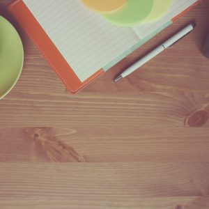 银行招聘网信息核对岗同事的工作照：一位工作人员正对照两份打印材料逐行核验报名截止日期，桌上放着放大镜与便签纸，神情专注